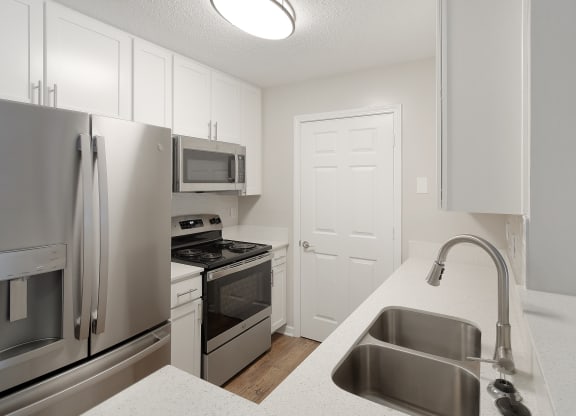 a kitchen with stainless steel appliances and white cabinets at The Woodlands Apartment Homes, Meridian