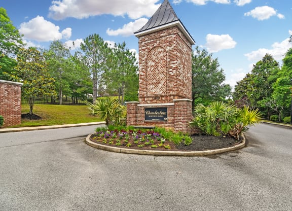 the roundabout in front of a brick tower with a sign on it at Charleston Apartment Homes, Mobile, Alabama