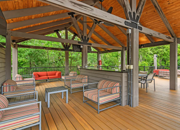 a covered patio with chairs and tables on a porch at Charleston Apartment Homes, Mobile, AL 36695