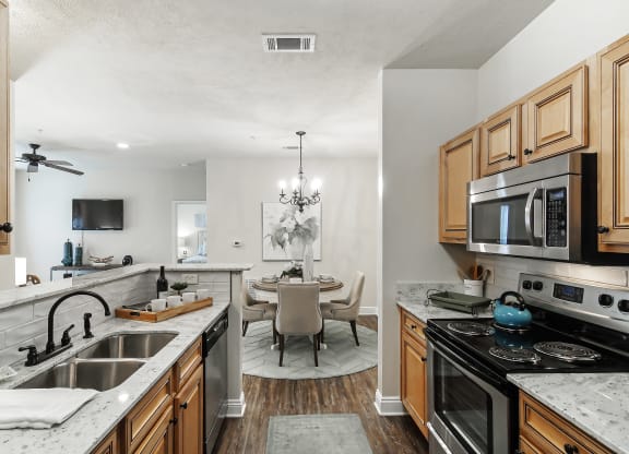 a kitchen with a sink and a stove and a dining room with a table at Charleston Apartment Homes, Alabama