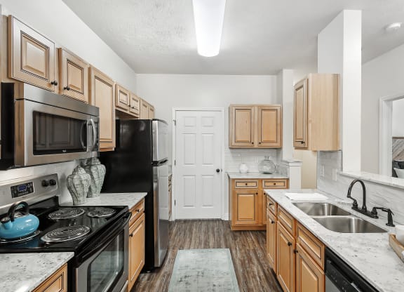 a kitchen with wooden cabinets and black appliances at Charleston Apartment Homes, Mobile, AL