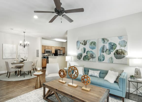 a living room with a blue couch and a ceiling fan at Charleston Apartment Homes, Mobile, 36695