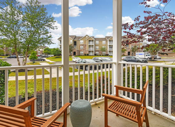 a porch with two wooden benches and a parking lot at Charleston Apartment Homes, Alabama 36695
