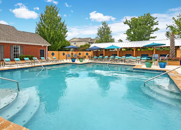 our resort style swimming pool is next to our building with lounge chairs at Summit of Shreveport Apartments, Shreveport, LA