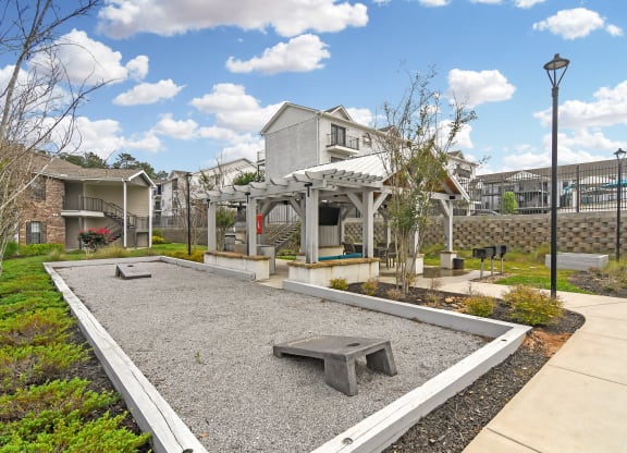 a courtyard with a bench and a house in the background at Parkwest Apartment Homes, Hattiesburg, MS