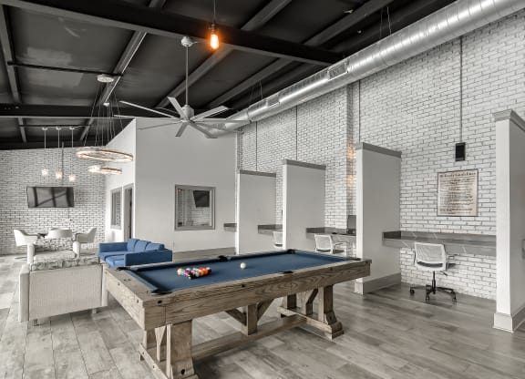 a pool table in a living room with white brick walls at Parkwest Apartment Homes, Hattiesburg, MS