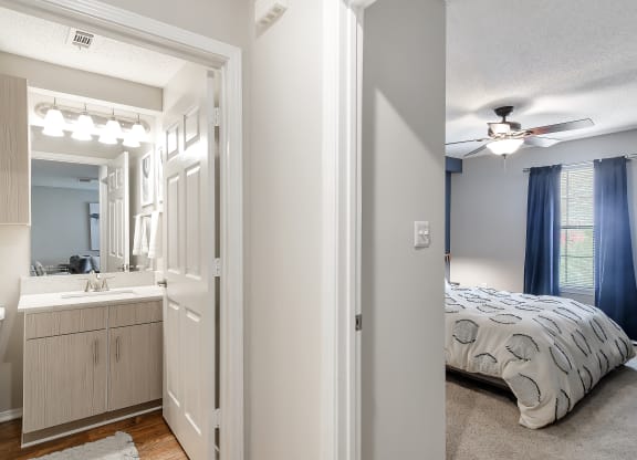 a bedroom and a bathroom with a bed and a ceiling fan at Parkwest Apartment Homes, Hattiesburg, 39402