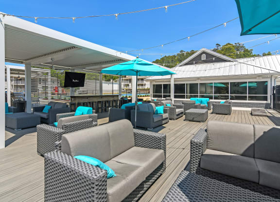 a roof top patio with chairs and umbrellas and a tv at The Woodlands Apartment Homes, Meridian, MS