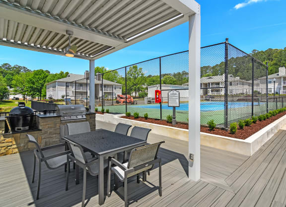 a covered patio with a table and chairs next to a pool at The Woodlands Apartment Homes, Mississippi 39301