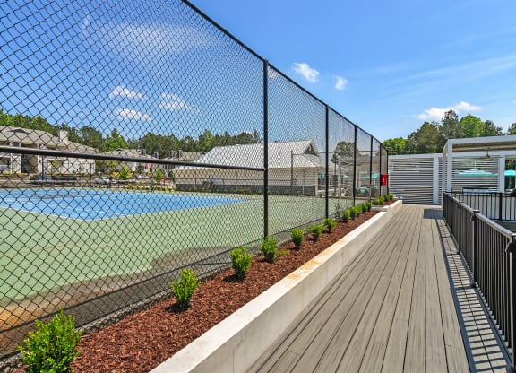 a tennis court is enclosed by a chain link fence at The Woodlands Apartment Homes, Mississippi 39301