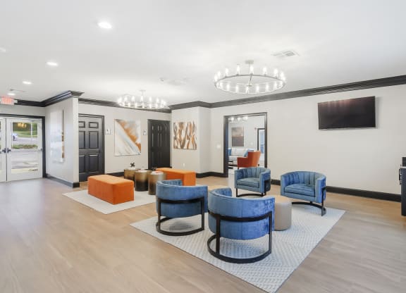 a lobby with chairs and tables and a television at The Woodlands Apartment Homes, Meridian