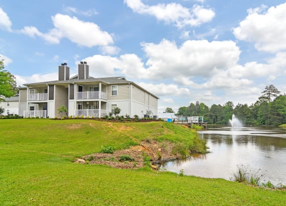 the view of a building next to a lake with a fountain at The Woodlands Apartment Homes, Meridian