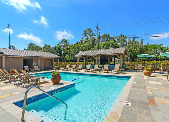 our resort style swimming pool is filled with lounge chairs and umbrellas at Highpointe Apartment Homes, Mississippi
