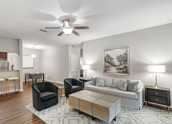 Open living room with a couch and chairs and a ceiling fan at Highpointe Apartment Homes, Brandon, Mississippi