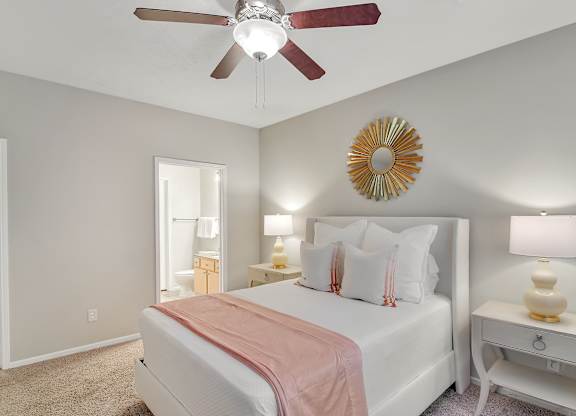 A bedroom with a bed, nightstands, and a ceiling fan at Ashford Place Apartments, Flowood, MS 39232