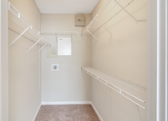 a spacious walk in closet with white rails and shelves and a white wall at Legacy Apartment Homes in Mississippi 39157
