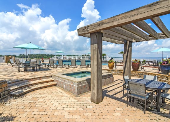 the patio has a hot tub and tables with umbrellas at Lakeshore Pointe Apartment Homes, Brandon, MS, 39047