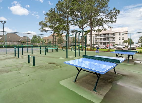 a tennis court at a park with ping pong tables at Lakeshore Pointe Apartment Homes, Brandon, MS
