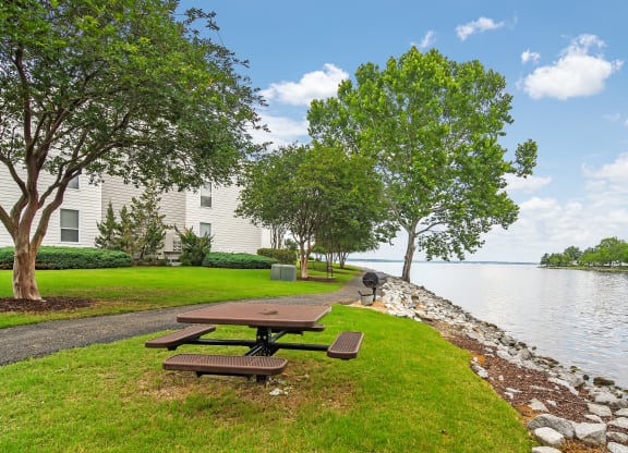 a picnic table on the grass next to the water at Lakeshore Pointe Apartment Homes, Brandon, 39047