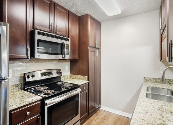 a kitchen with wood cabinets and stainless steel appliances and granite counter tops at Lakeshore Pointe Apartment Homes, Brandon, 39047