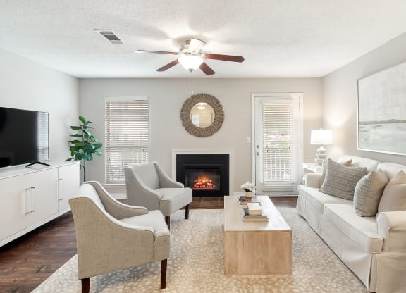 an open living room with a fireplace and a ceiling fan at Lakeshore Pointe Apartment Homes, Mississippi