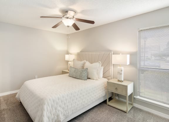 a bedroom with a large white bed and a ceiling fan at Lakeshore Pointe Apartment Homes, Brandon, MS