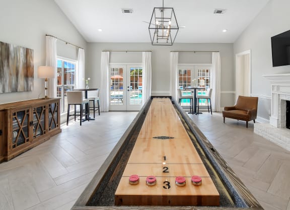 a long shuffleboard table in the middle of a living room with a fireplace at Bridgewater Apartment Homes, Brandon, MS