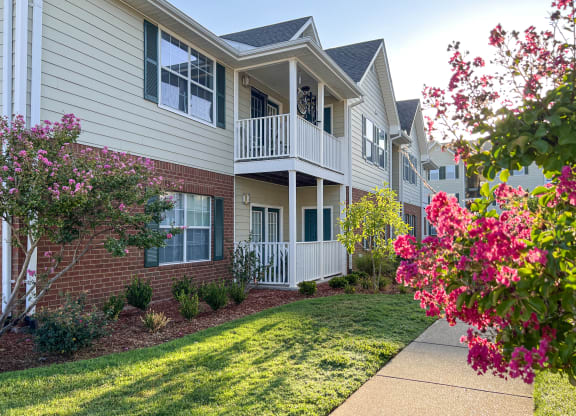 an exterior view of an apartment building with a lawn and flowers at The Madison Apartment Homes in Tyler, TX 