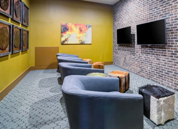a waiting room with blue chairs and a brick wall at The Retreat Apartment Homes in Williston, ND 58801