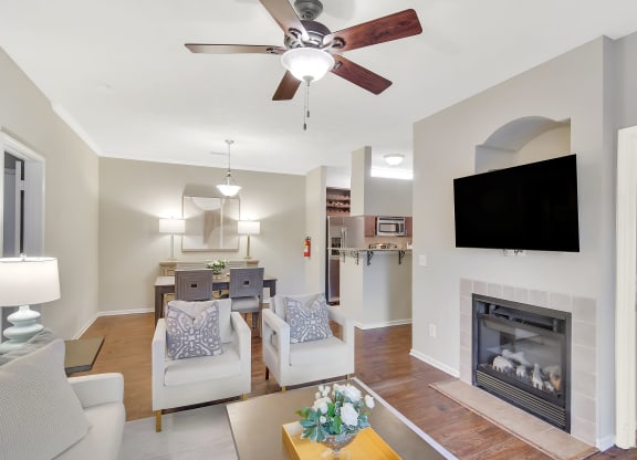 a living room with a fireplace and a ceiling fan at Ashford Place Apartment Homes, Flowood, MS 39232