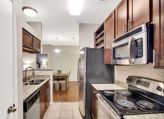 a kitchen with stainless steel appliances and wood cabinets at Ashford Place Apartment Homes, Mississippi 39232
