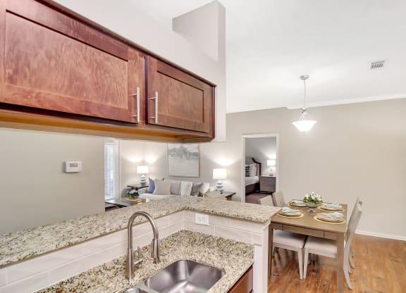 a kitchen with a sink and a dining table at Ashford Place Apartment Homes, Flowood, MS 39232