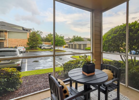 a patio with a table and chairs next to a large window at Ashford Place Apartment Homes, Flowood, MS 39232