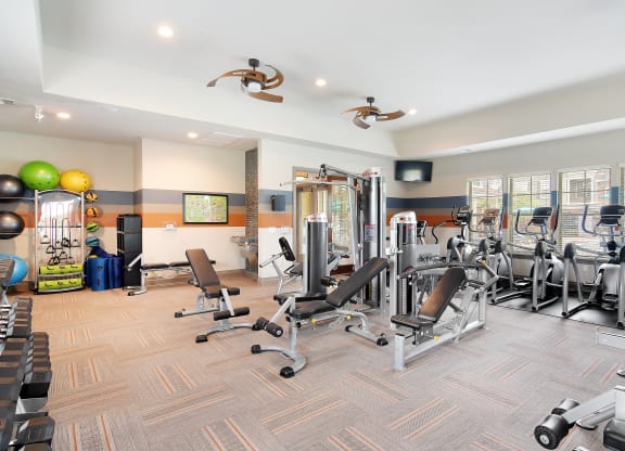 a gym with cardio machines and weights on a wooden floor at Audubon Park Apartment Homes, Louisiana