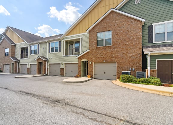 an empty driveway in front of a brick house with garages at Audubon Park Apartment Homes, Zachary