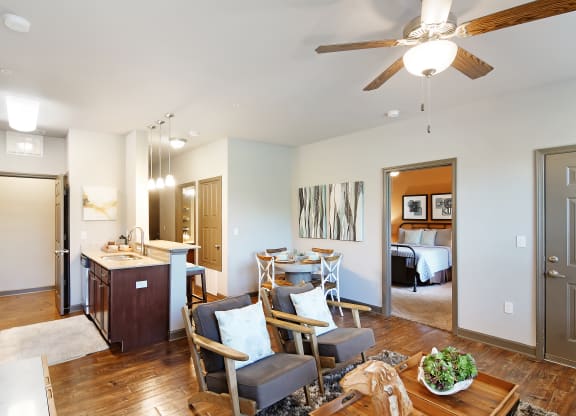 a living room with a dining room and a kitchen with a table and chairs at Audubon Park Apartment Homes, Zachary, 70791