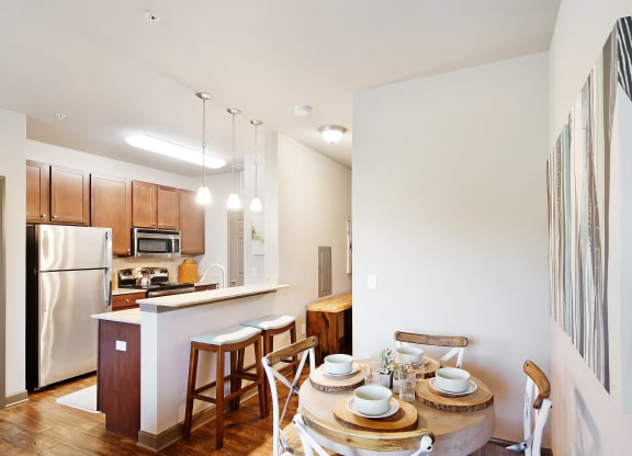 a kitchen and dining area with a wooden table and chairs and a refrigerator at Audubon Park Apartment Homes, Louisiana