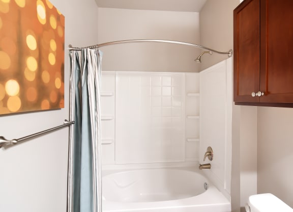 a bathroom with a white tub and a shower curtain at Audubon Park Apartment Homes, LA