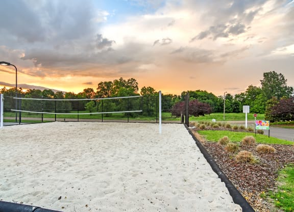 a sand volleyball court with a sunset in the background at Avalon Apartment Homes, Starkville, MS, 39759