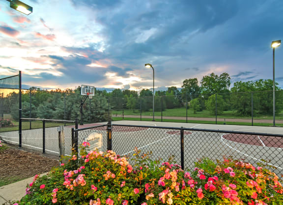 a basketball court at sunset with flowers and a fence at Avalon Apartment Homes, Starkville