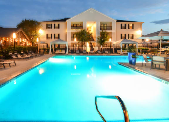 a swimming pool at night with a hotel in the background at Avalon Apartment Homes, Starkville, 39759