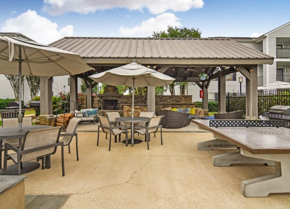 a patio with tables and umbrellas and a fire pit at Avalon Apartment Homes, Mississippi