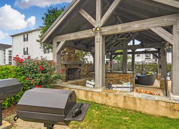a backyard with a grill and a patio with a fireplace at Avalon Apartment Homes, Starkville, 39759