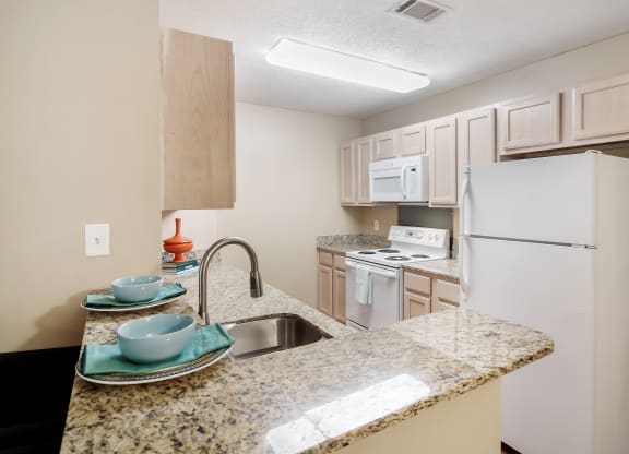 a kitchen with white appliances and a granite counter top at Avalon Apartment Homes, Starkville, 39759
