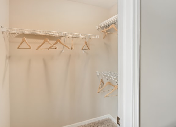 a walk in closet with hanging racks and a door to it at Avalon Apartment Homes, Starkville, MS
