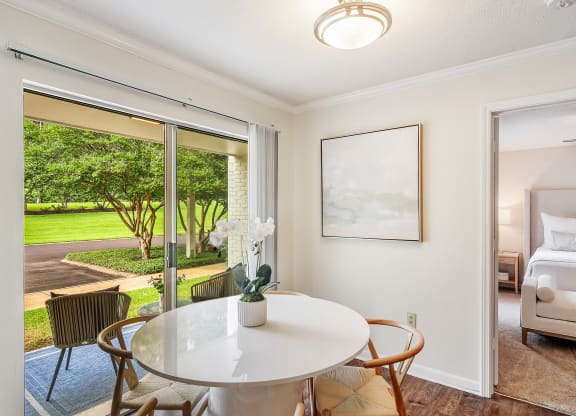 a dining area with a table and chairs and a bedroom with a bed at Cambridge Station Apartment Homes, Mississippi