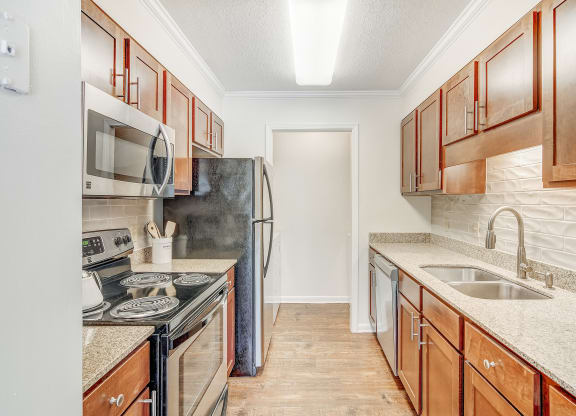 a kitchen with wood cabinets and granite counter tops and a sink at Cambridge Station Apartment Homes, Mississippi, 38655