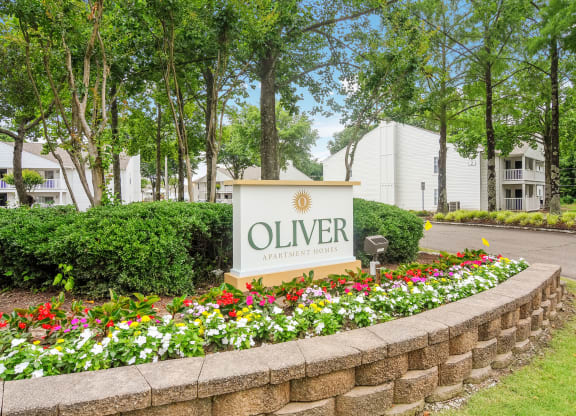 an olivier apartments sign in front of a stone wall and flowers at The Oliver Apartment Homes, Olive Branch, MS, 38654