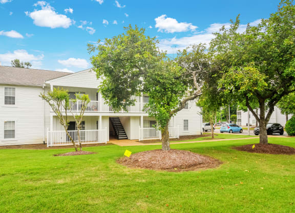 the outlook of a white condominium building with treesat The Plantation Apartment Homes, Mississippi, 38654