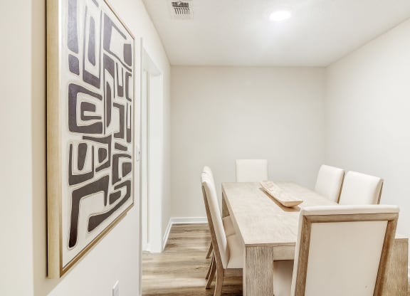 a dining room with a table and chairs and a painting on the wall at The Oliver Apartment Homes, Olive Branch, MS